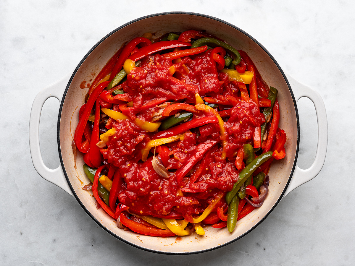 Pureed tomatoes added to pepper mixture in pan.