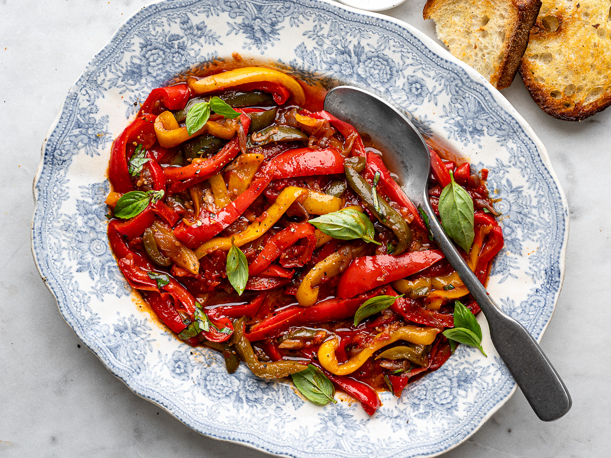 Peperonata served on large blue platter with crusty bread on the side.