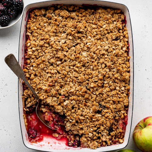 Apple Blackberry Crumble in baking dish with some of the filling exposed.
