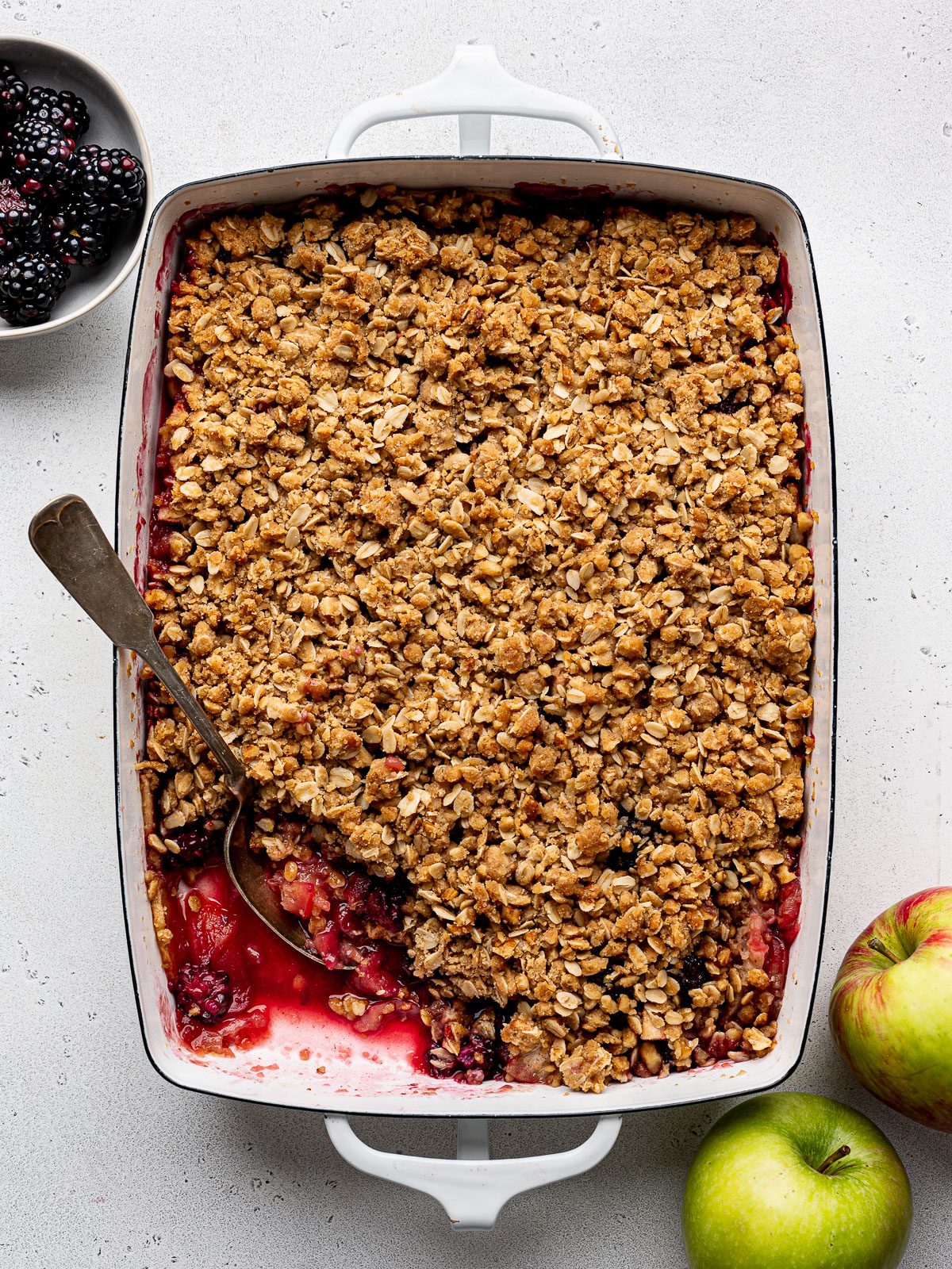 Apple Blackberry Crumble in baking dish with some of the filling exposed.