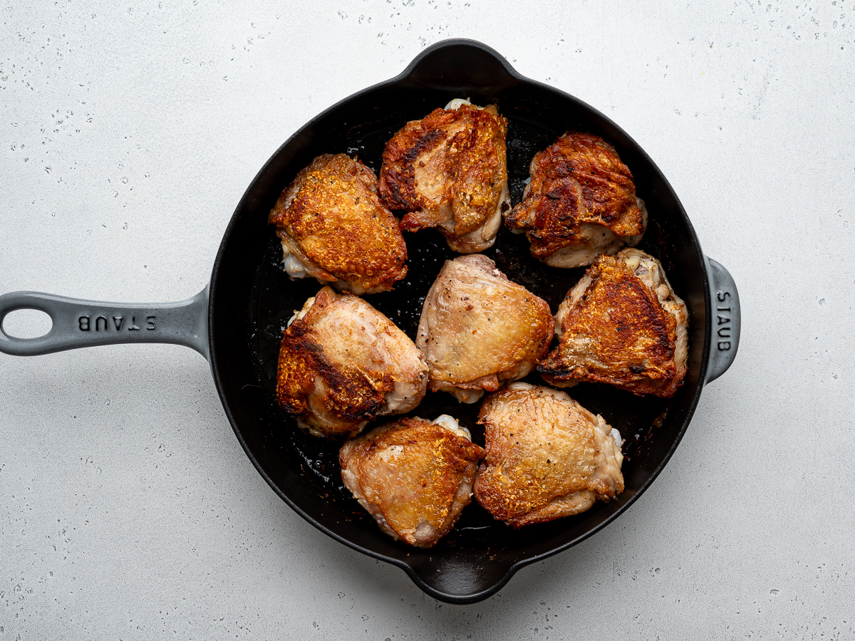 Seared chicken thighs in skillet.
