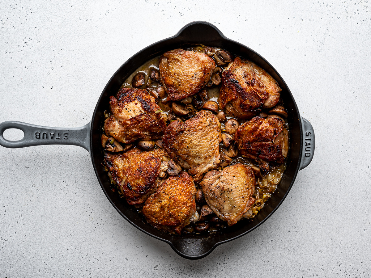 Cooked chicken in skillet with mushrooms. 