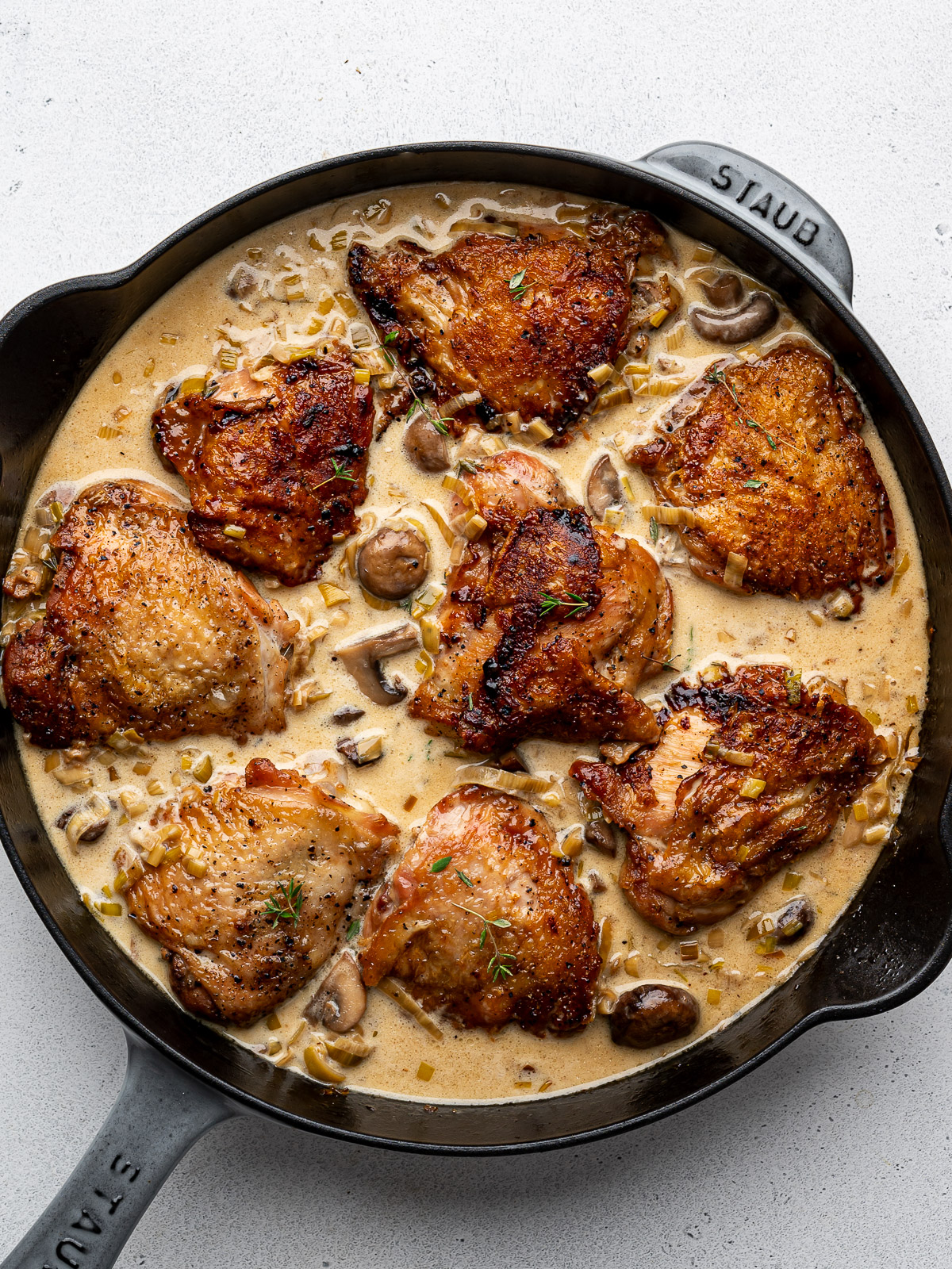 Chicken thighs in skillet with cream sauce. 