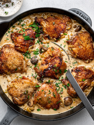 The finished dish of creamy chicken and leeks in the skillet with a large serving spoon.