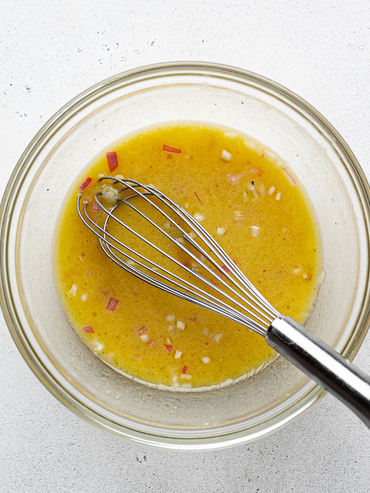 Mixed dressing in a small glass bowl with whisk.