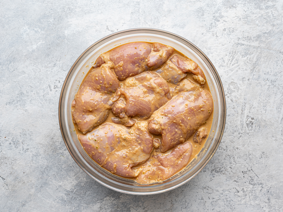 Chicken thighs marinating in glass bowl. 
