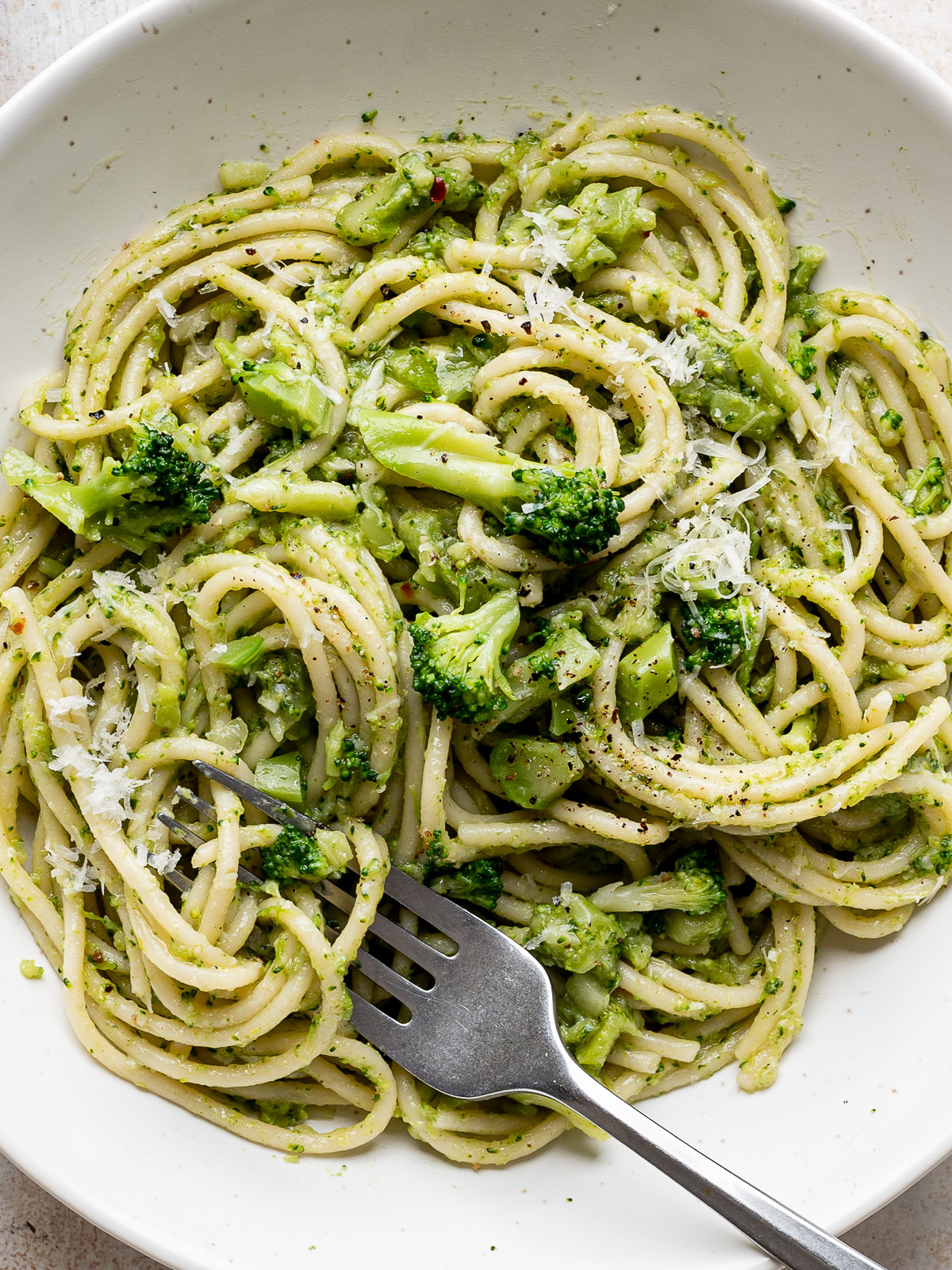 Close-up of broccoli pasta in white bowl with fork. 