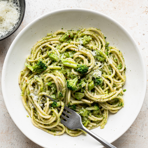 Broccoli Pasta served in white bowl with grated pecorino on the side.