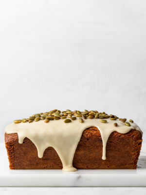 Side view of gluten-free pumpkin loaf drizzled with glaze and topped with pepitas.