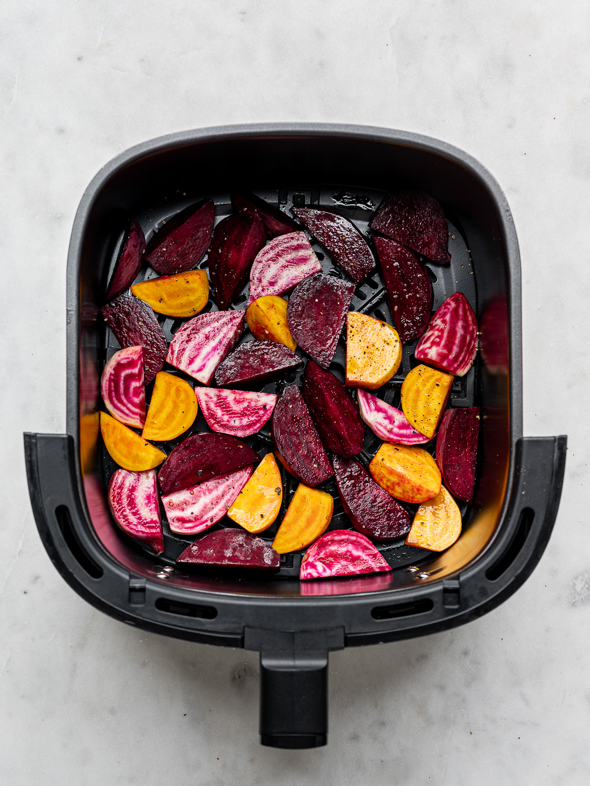 Raw, sliced beets in air fryer basket.