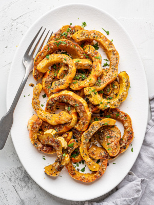 Roasted Parmesan crusted carnival squash slices served on a white platter.
