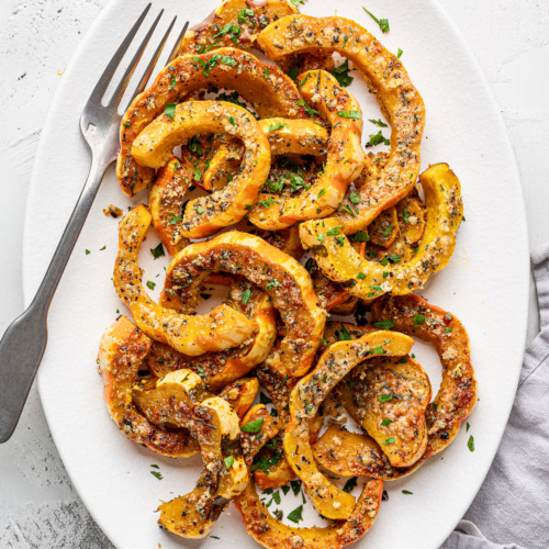 Roasted Parmesan crusted carnival squash slices served on a white platter.