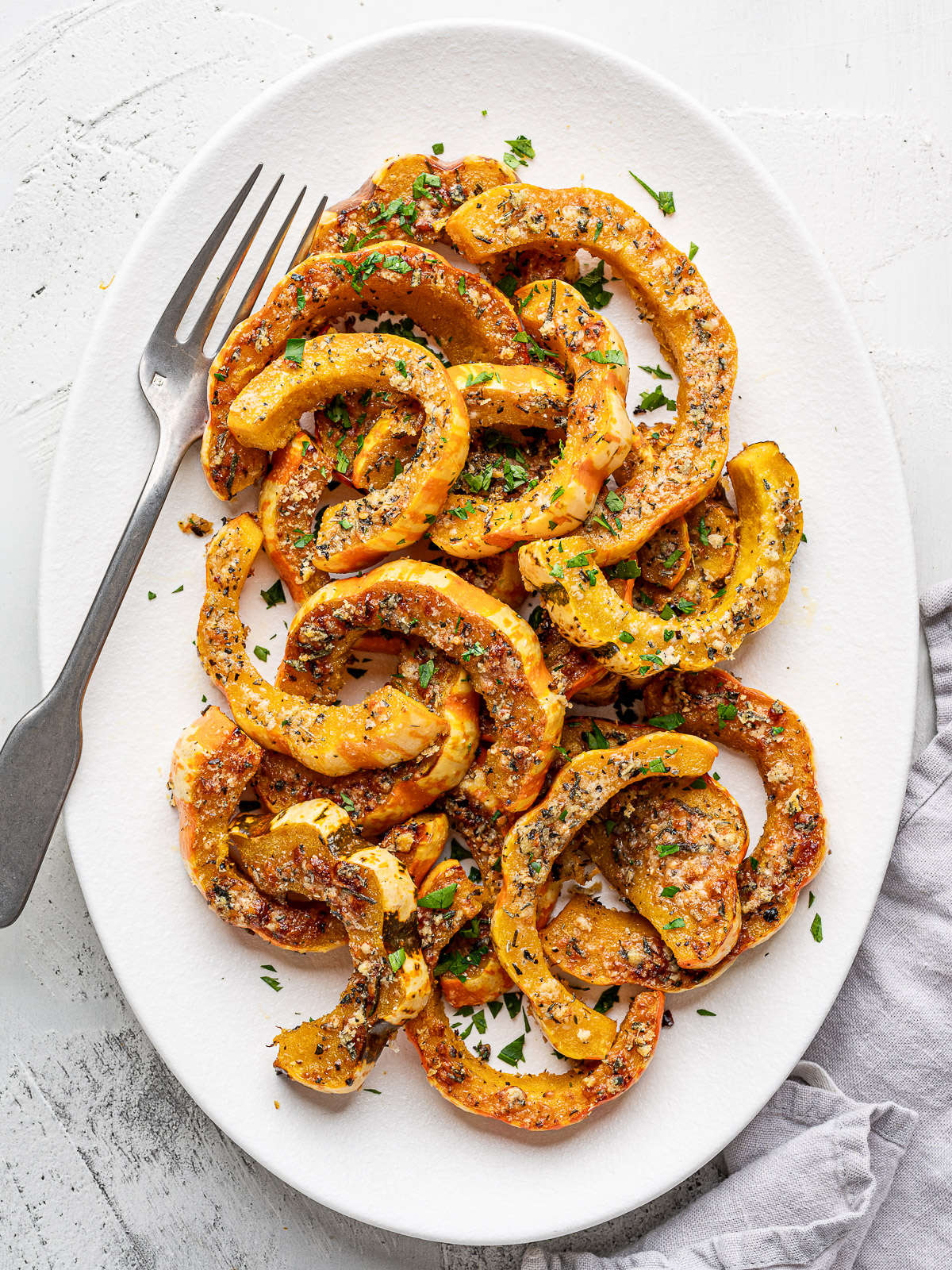Roasted Parmesan crusted carnival squash slices served on a white platter.