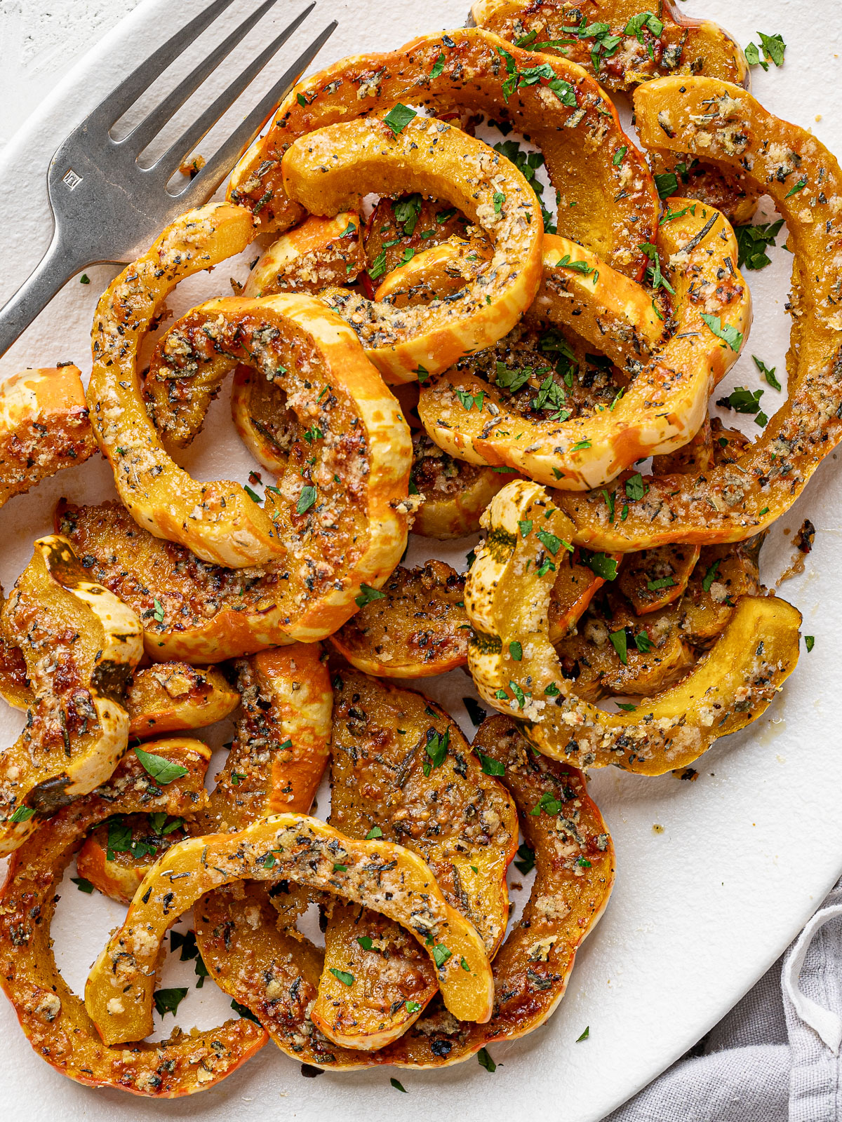 Close-up of Roasted Parmesan crusted carnival squash slices served on a white platter.