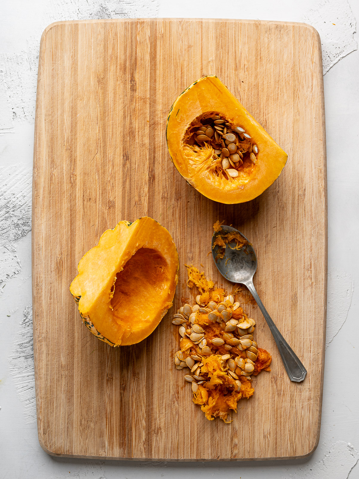 Carnival squash halved on a cutting board with seeds scooped out. 