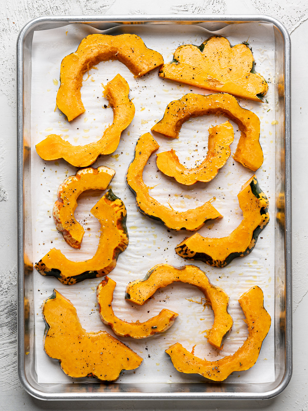 Un-baked squash slices on baking sheet. 