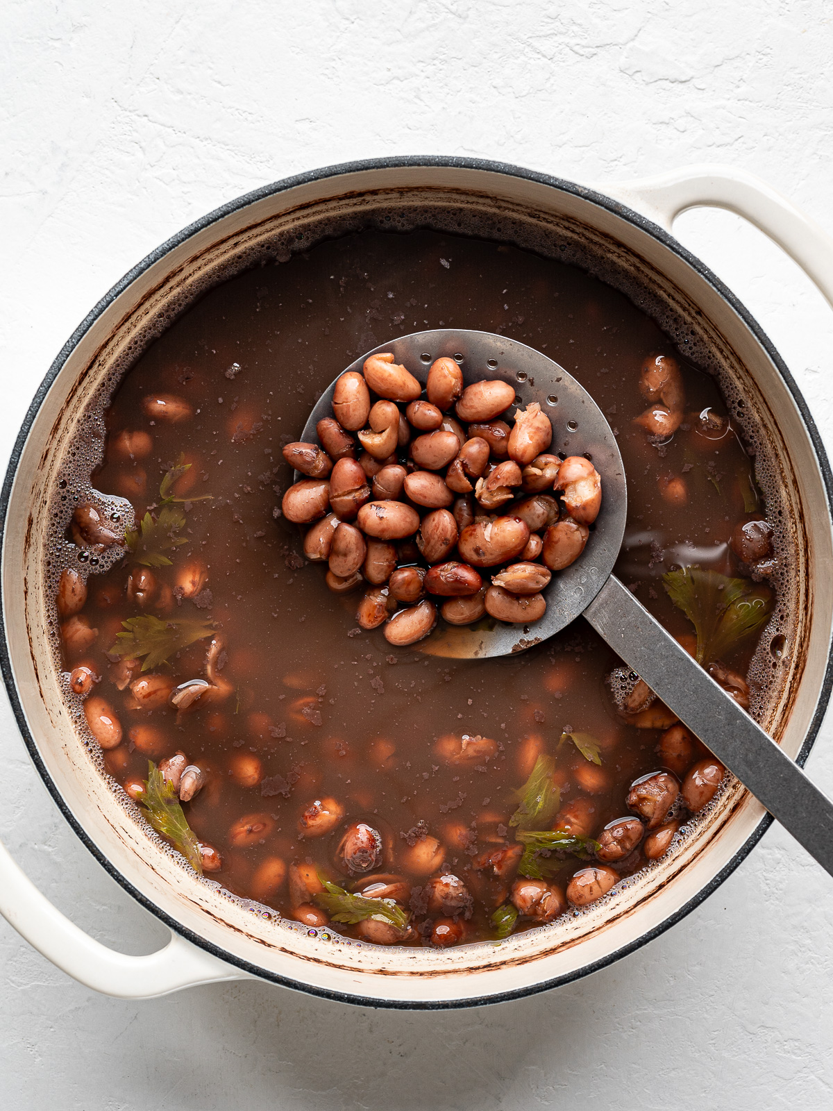 Cooked beans in pot with ladle.
