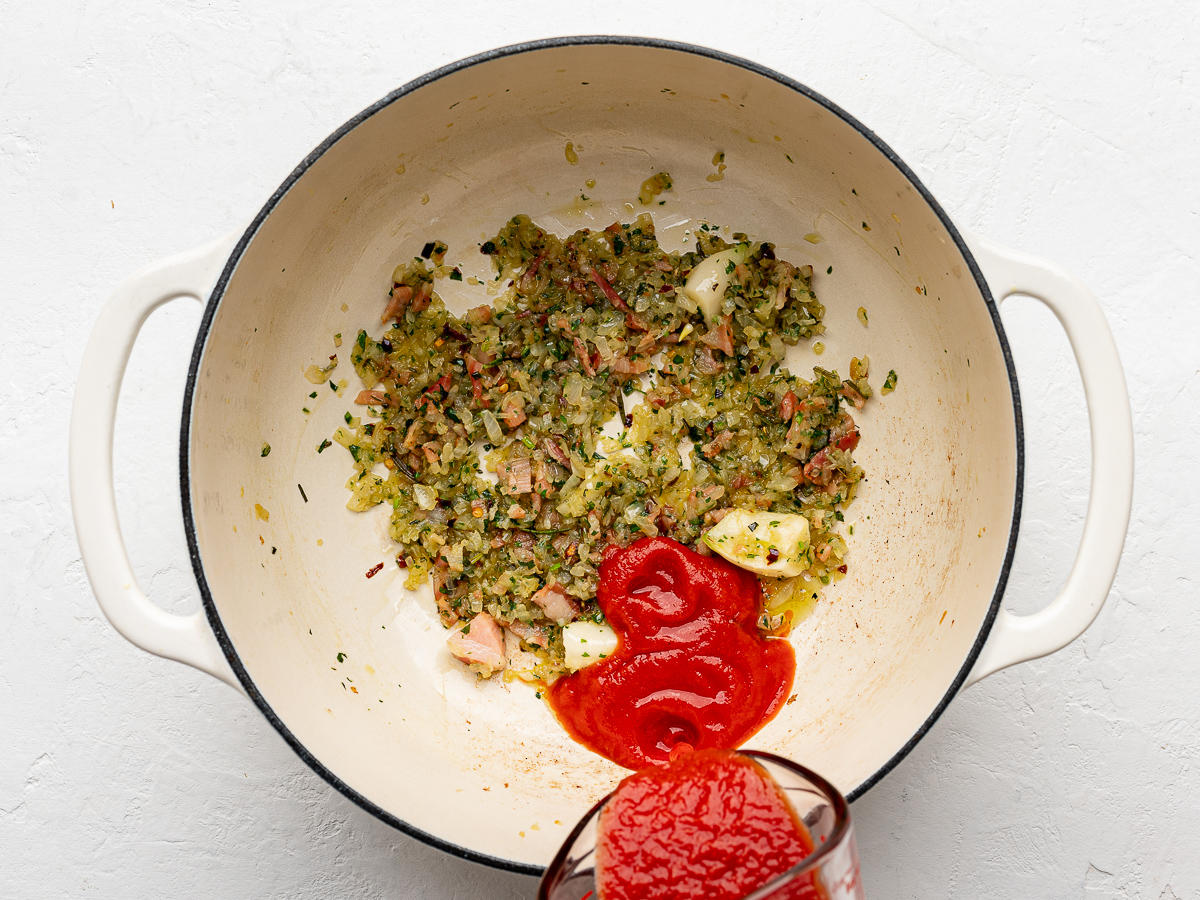 Adding passata to pot with onion mixture. 