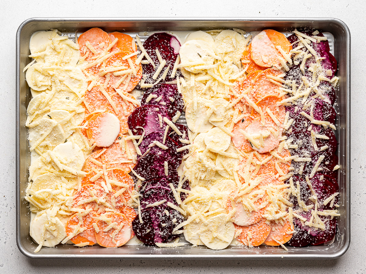 Grated cheese mixture sprinkled over layer of uncooked root vegetables. 