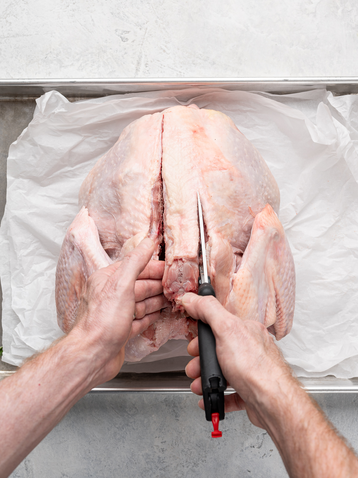 Cutting backbone out of turkey with poultry shears.