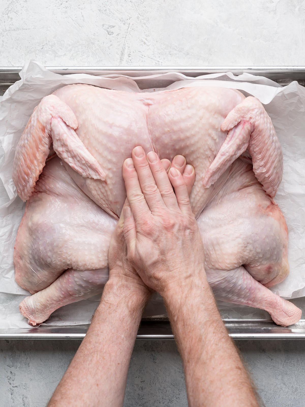 Flattening the turkey by pressing on the breasts with two hands. 