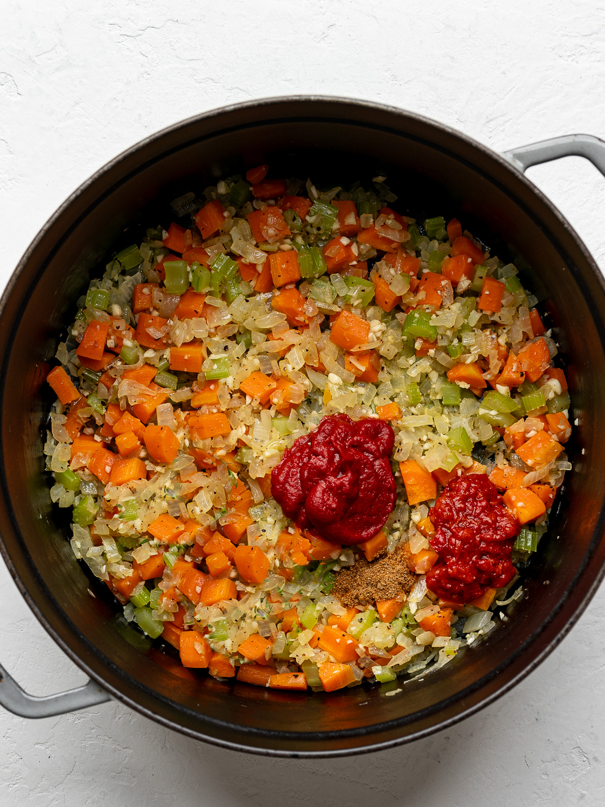 Sautéed diced onions, carrots, celery and garlic with dollops of tomato paste and harissa in Dutch oven.