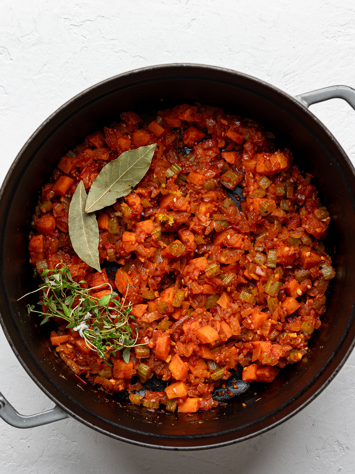 Bay leaves and a bundle of thyme sprigs added to the onion mixture in Dutch oven.