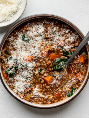Lentil and brown rice soup served in a bowl sprinkled with grated parmesan.