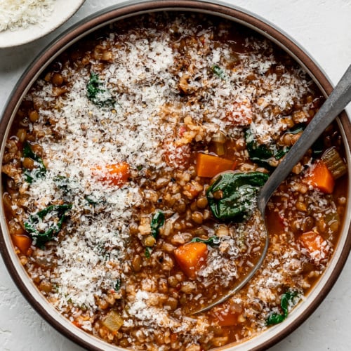 Lentil and brown rice soup served in a bowl sprinkled with grated parmesan.