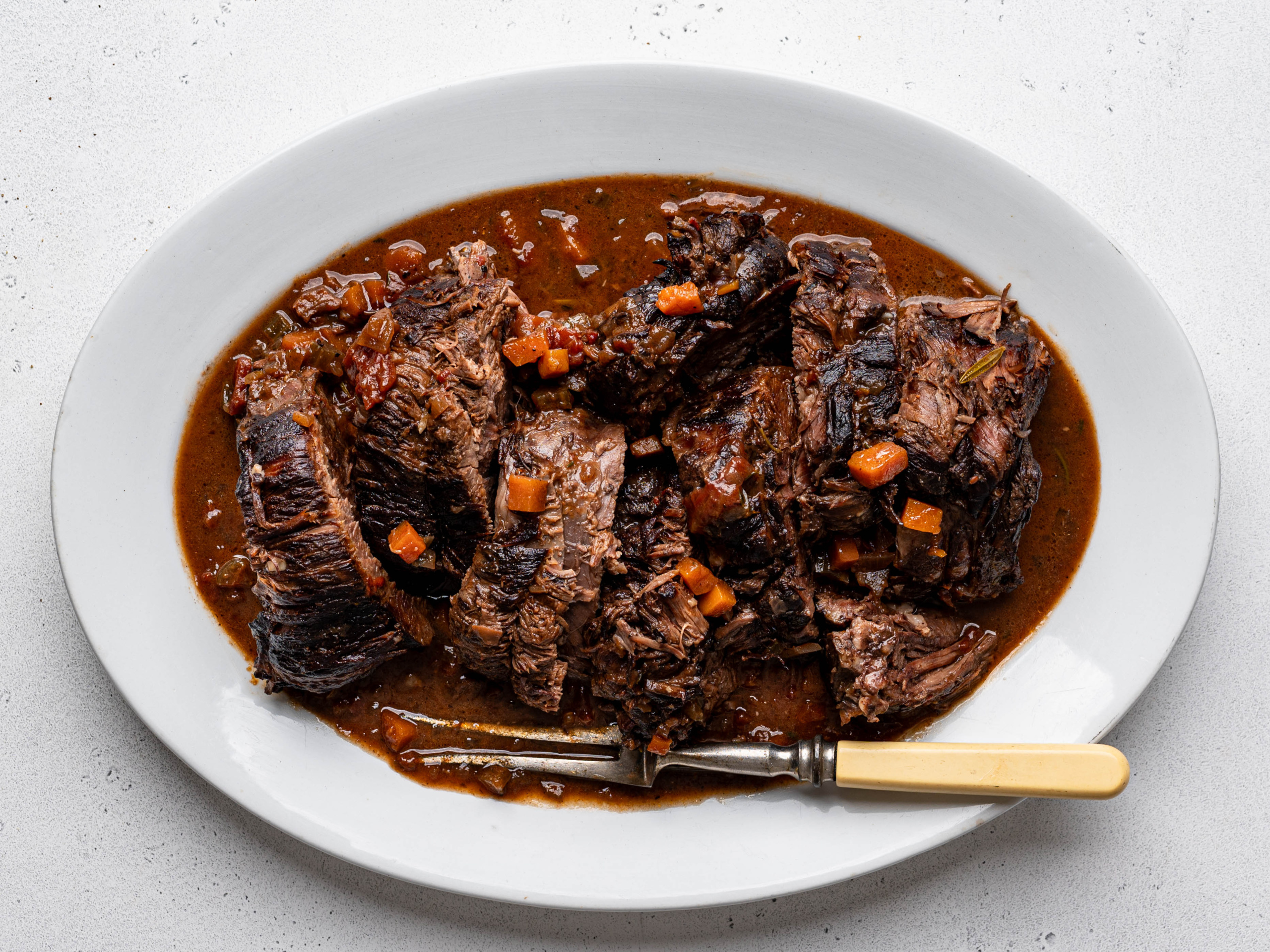 Sliced Stracatto di manzo (Italian pot roast) served on a large white platter.