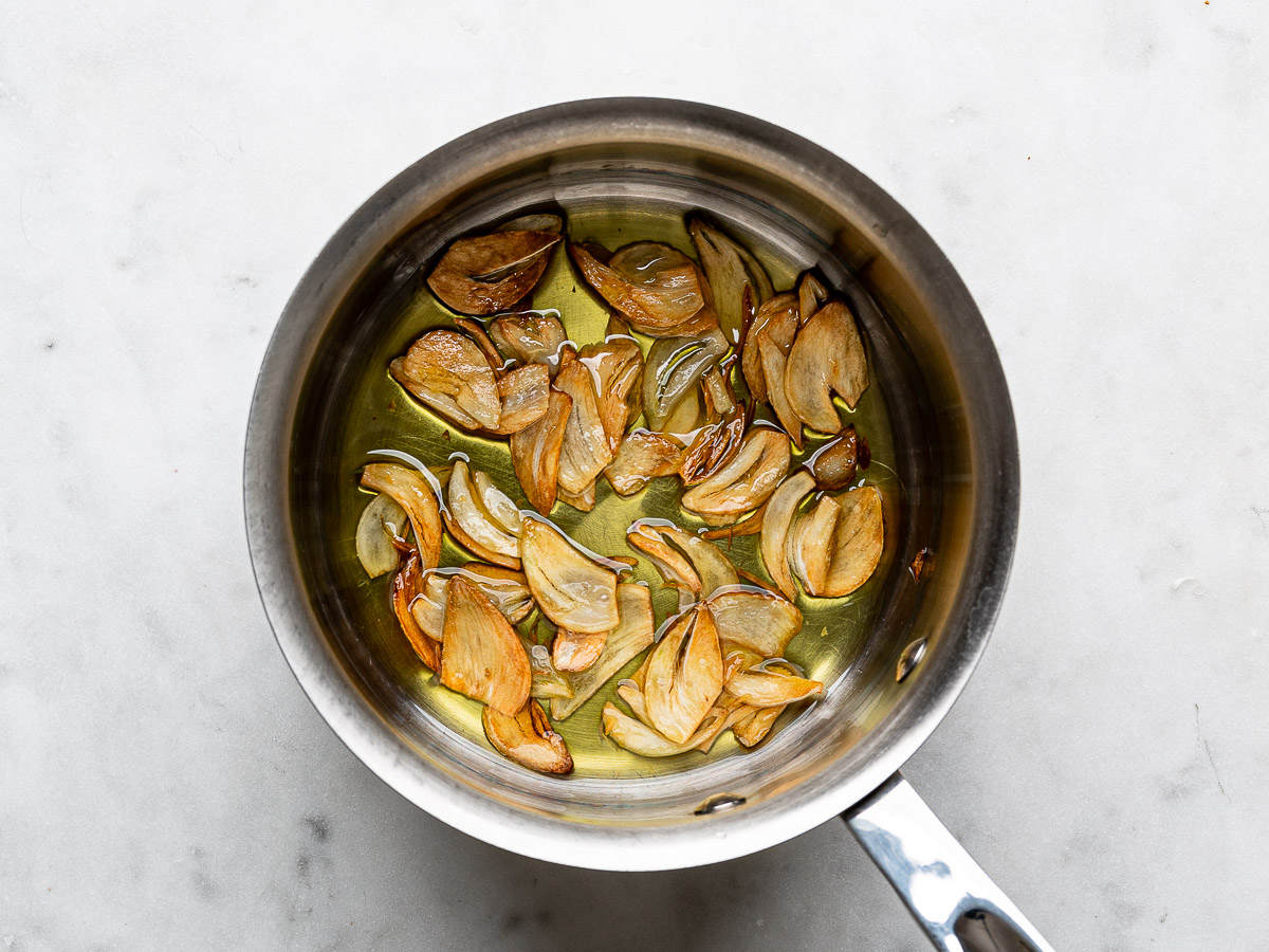 Fried garlic chips in saucepan with olive oil. 
