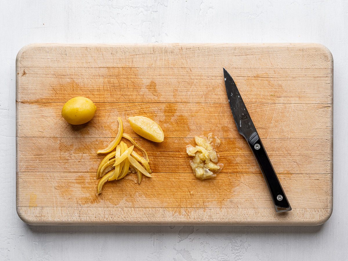 Removing pulp from preserved lemons and slicing the skin.