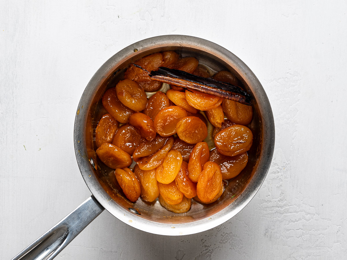 Caramelized apricots in saucepan with cinnamon stick.