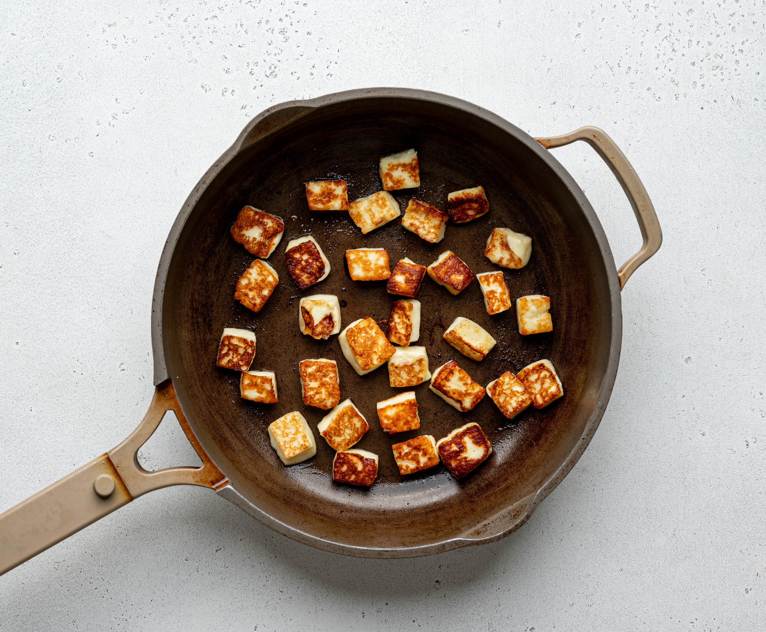 Fired halloumi cubes in skillet. 