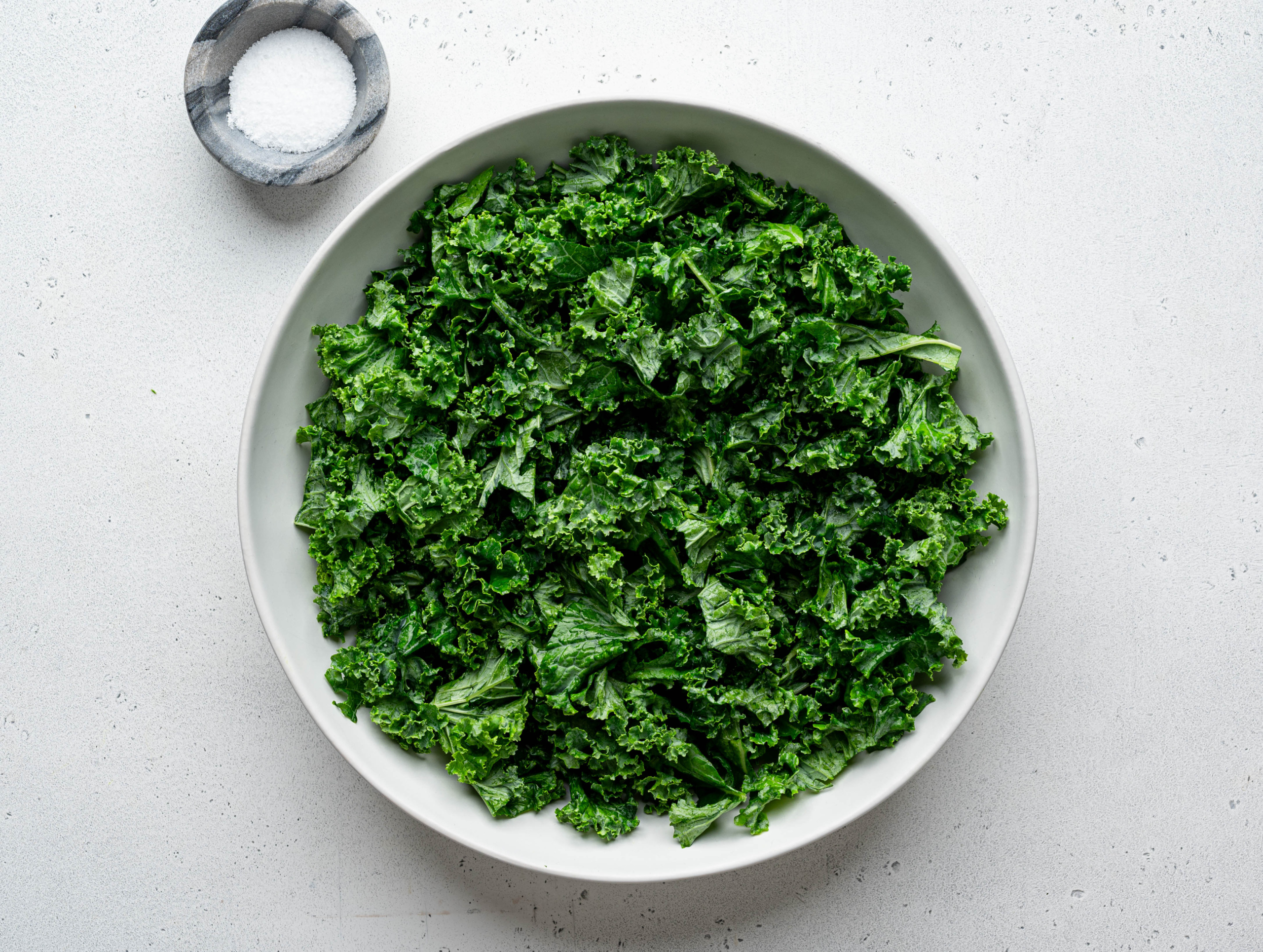 Massaged chopped kale in white salad bowl. 
