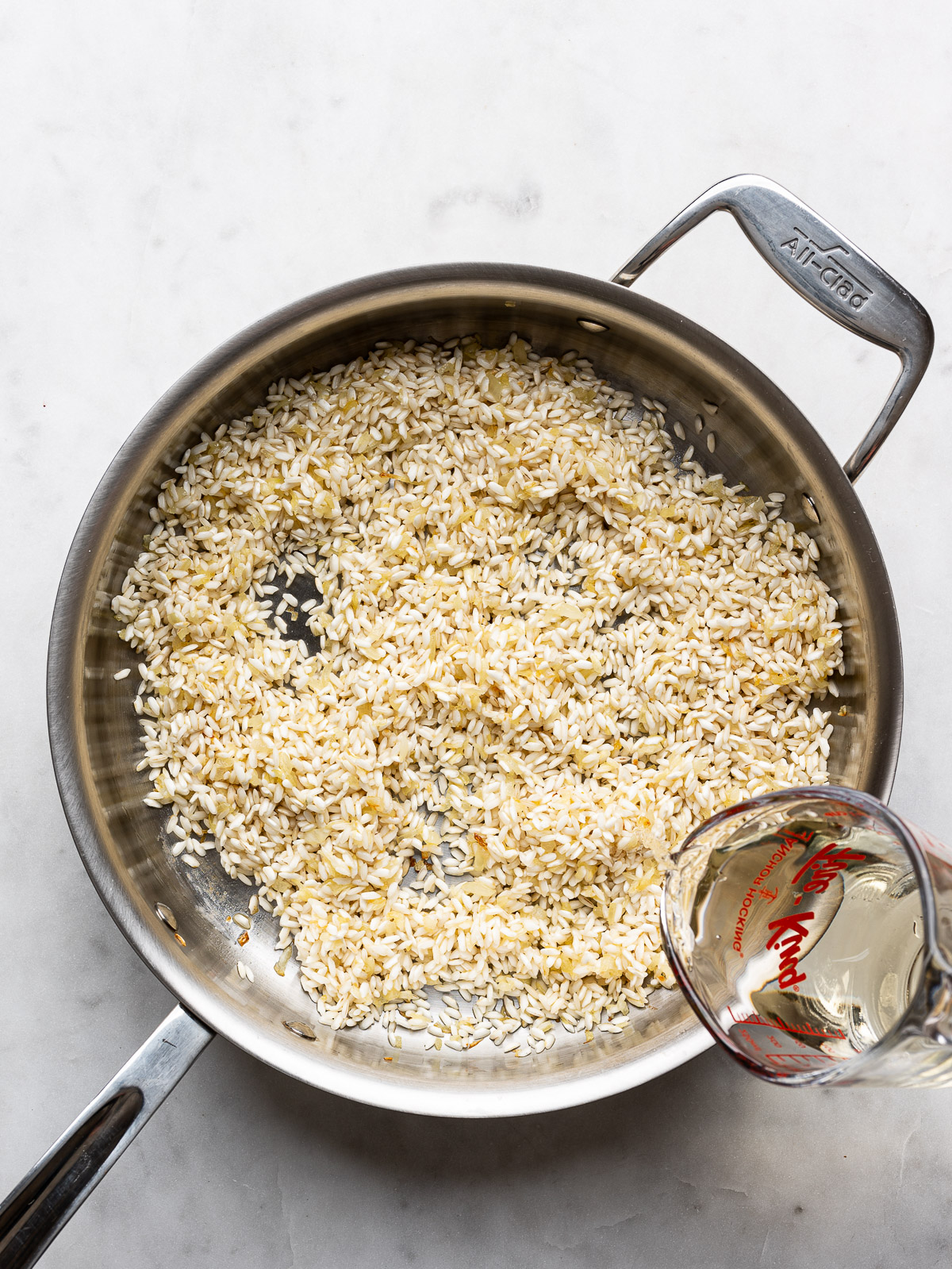 Adding wine to onion and rice mixture. 