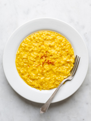 Risotto milanese served in a shallow white bowl.