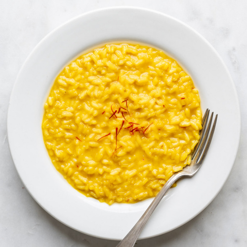 Risotto milanese served in a shallow white bowl.