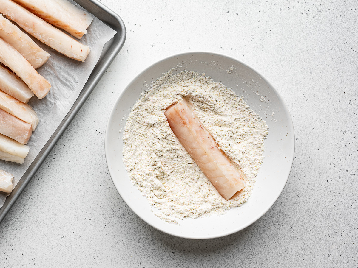 Coating fish pieces with dry flour mixture. 