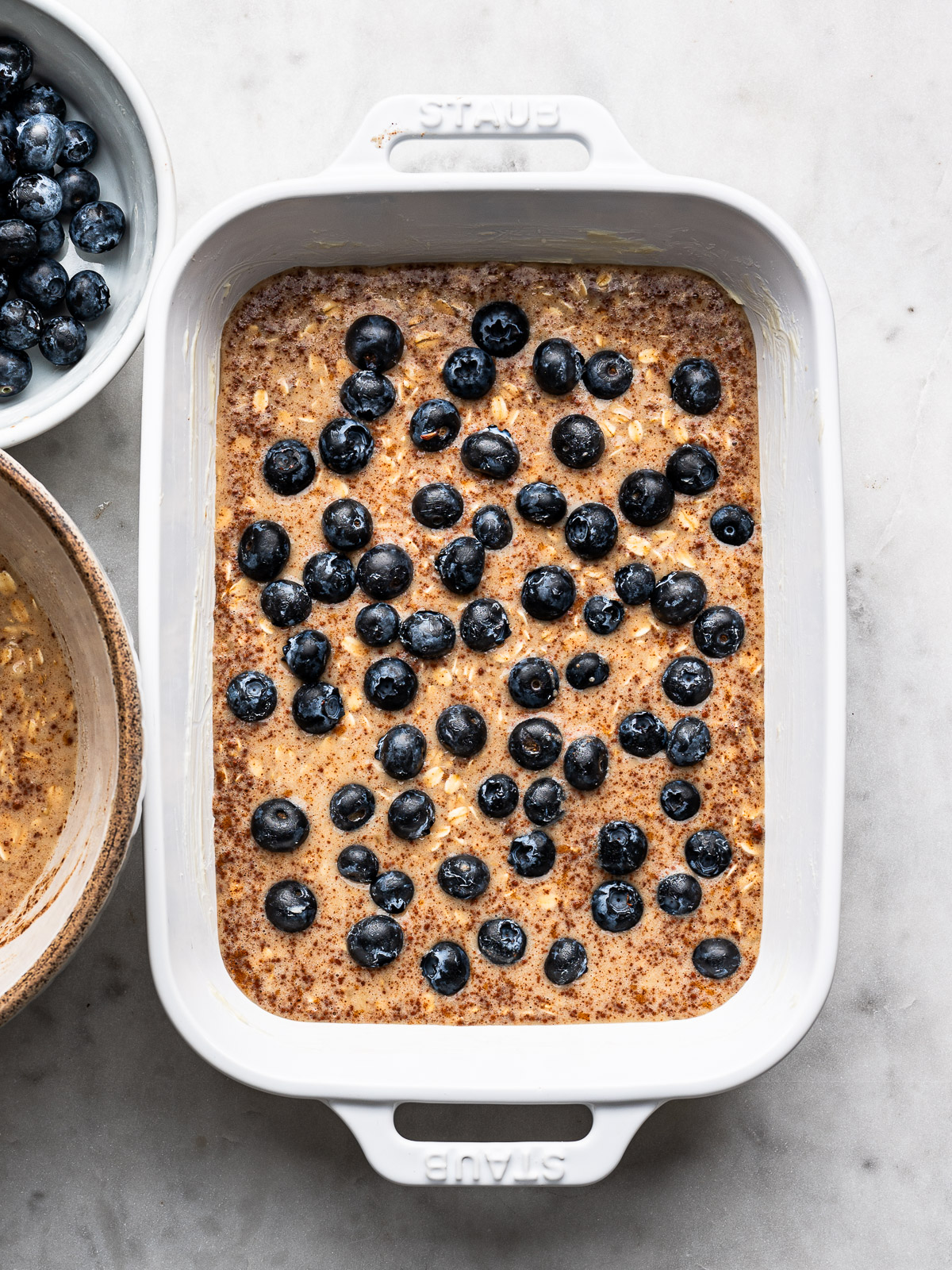 Half of oat mixture in baking dish topped with half of the blueberries.  