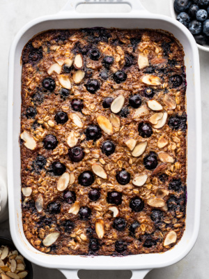 Close up of Blueberry Baked Oatmeal topped with sliced toasted almonds in white rectangular baking dish.
