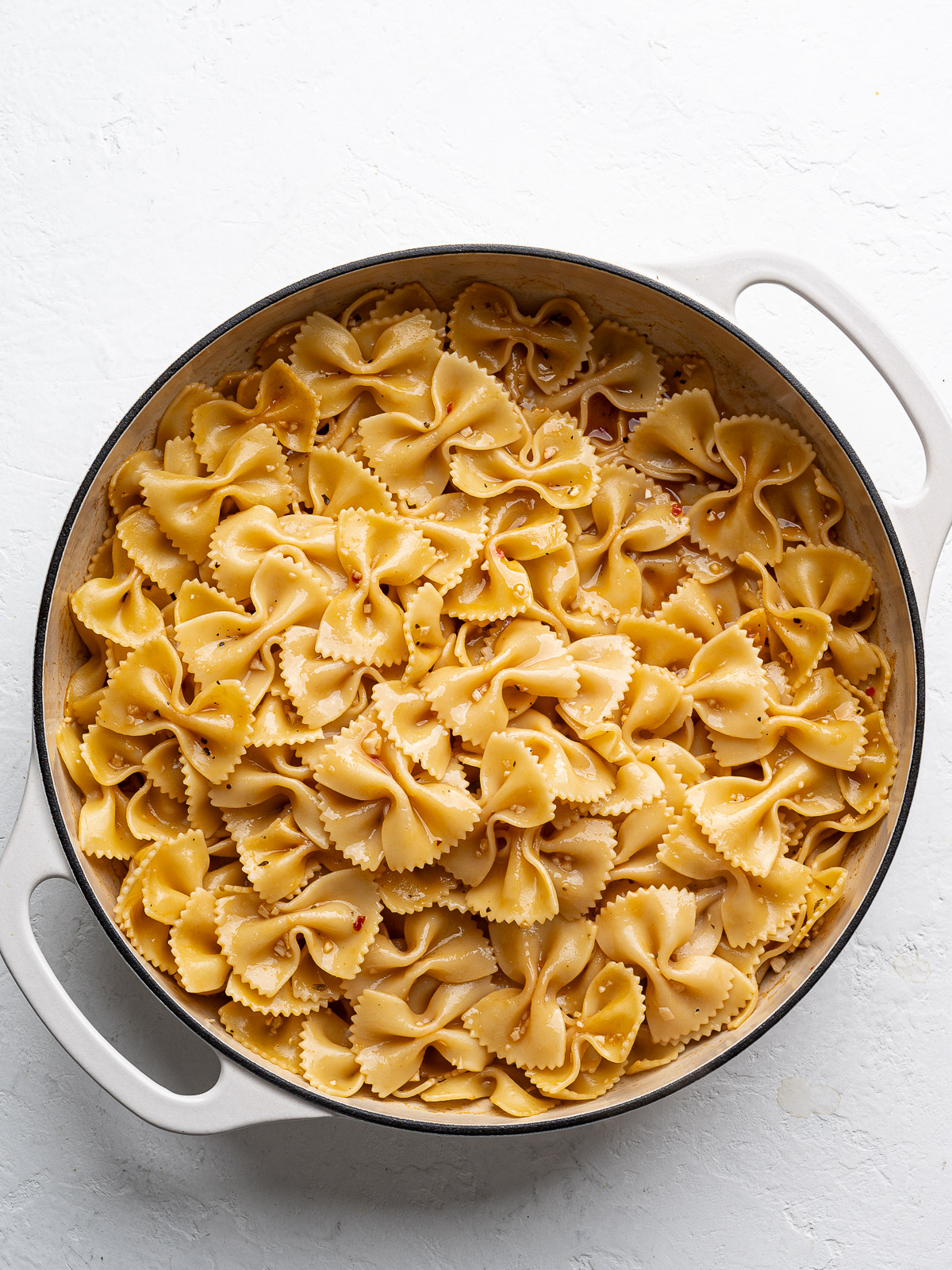 Dry bow-tie pasta added to skillet with chicken broth.