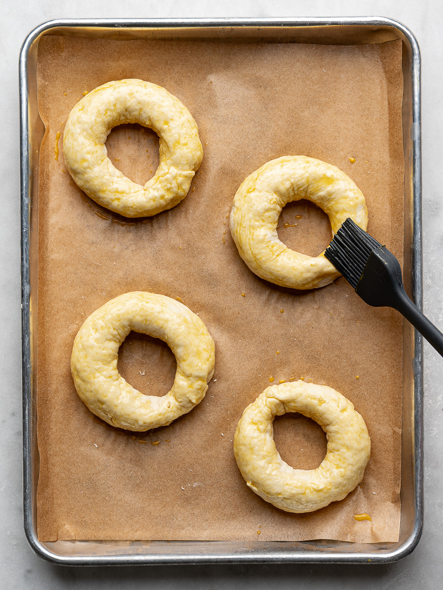 Brushing egg wash on 4 un-baked bagels. 