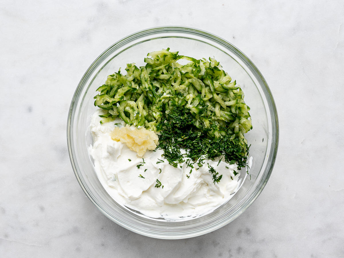 Tzatziki ingredients in glass mixing bowl. 