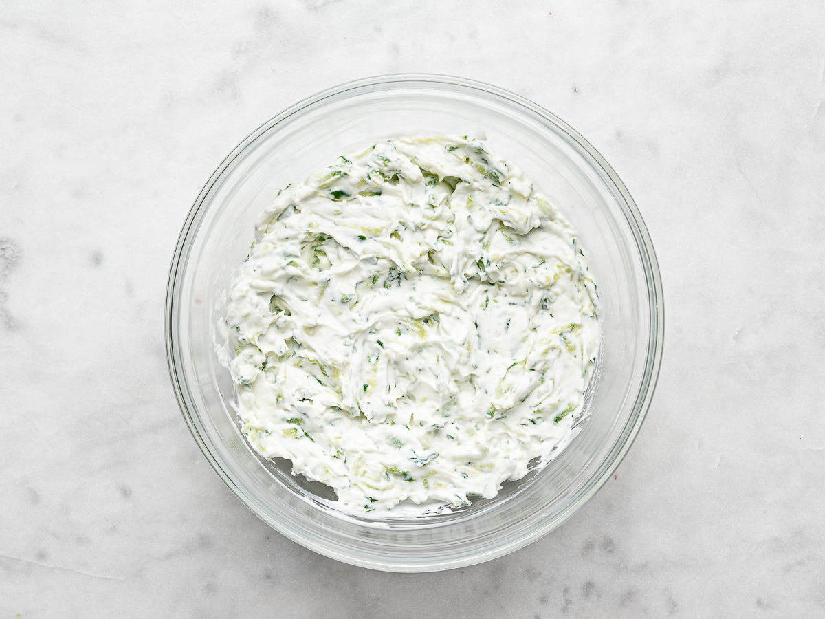 Prepared tzatziki sauce in glass mixing bowl. 
