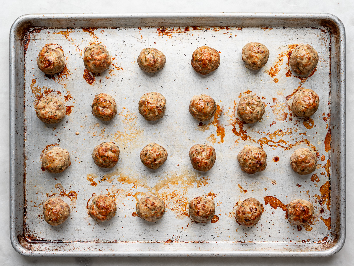 Baked meatballs on cookie sheet.