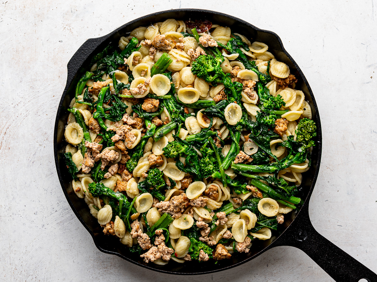 Cooked orecchiette pasta added to the sausage and rapini mixture in skillet. 