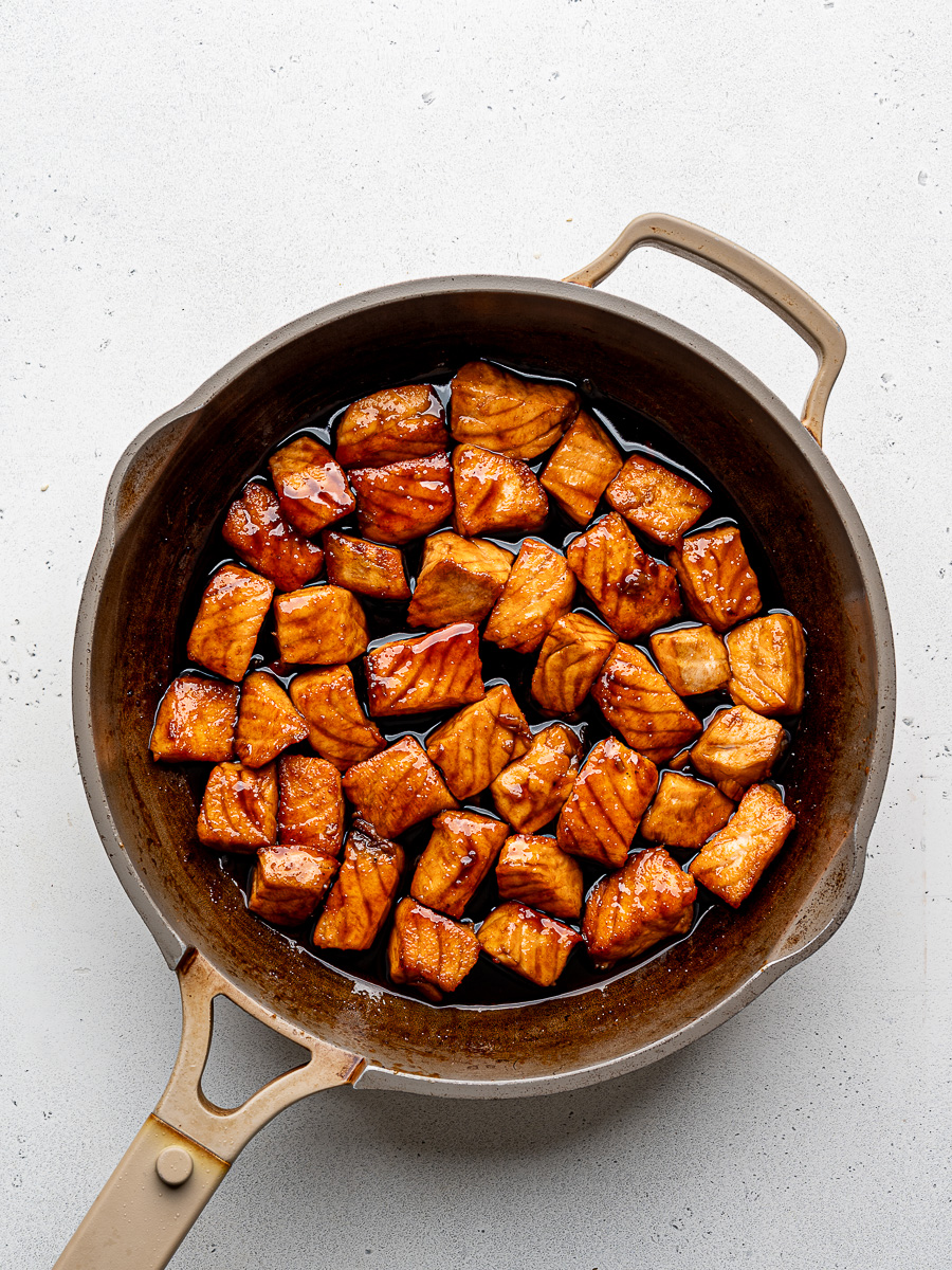 Seared salmon bites in skillet with honey-soy glaze. 
