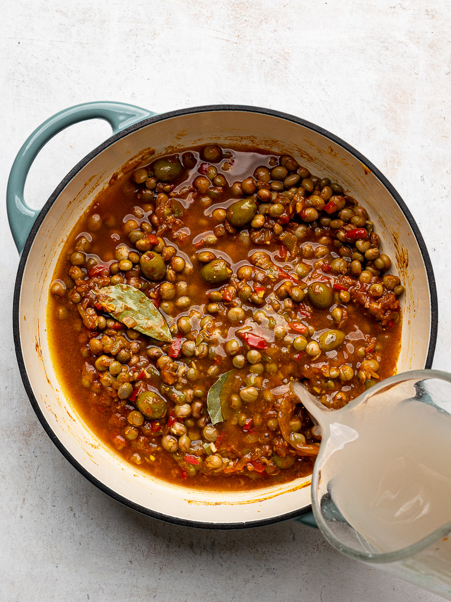 Pouring water over pigeon peas in pot. 