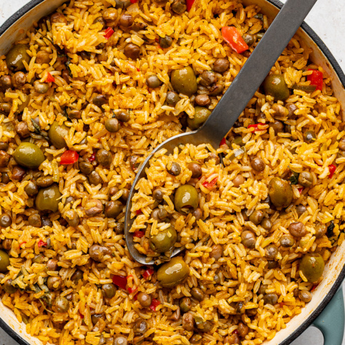 Cooked arroz con gandules in pot with large serving spoon.